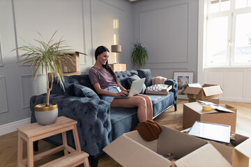 Happy woman using computer in her new apartment.