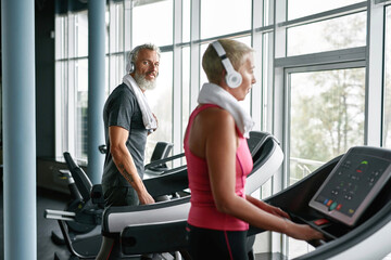 Sporty couple training on treadmill in fitness gym