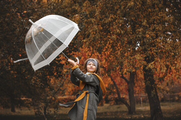 Beautiful little sweet girl child happy in autumn walks in nature with an umbrella under a leaf fall