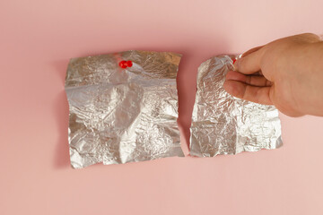 A man's hand pierces the Rectangular pieces of crumpled foil wit