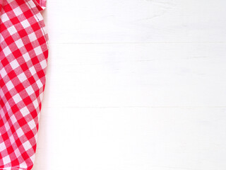 Top view, close-up of red and white checkered fabric or napkin on white table background. Concept kitchen utensils and tableware. Top view, flat lay with copy space..