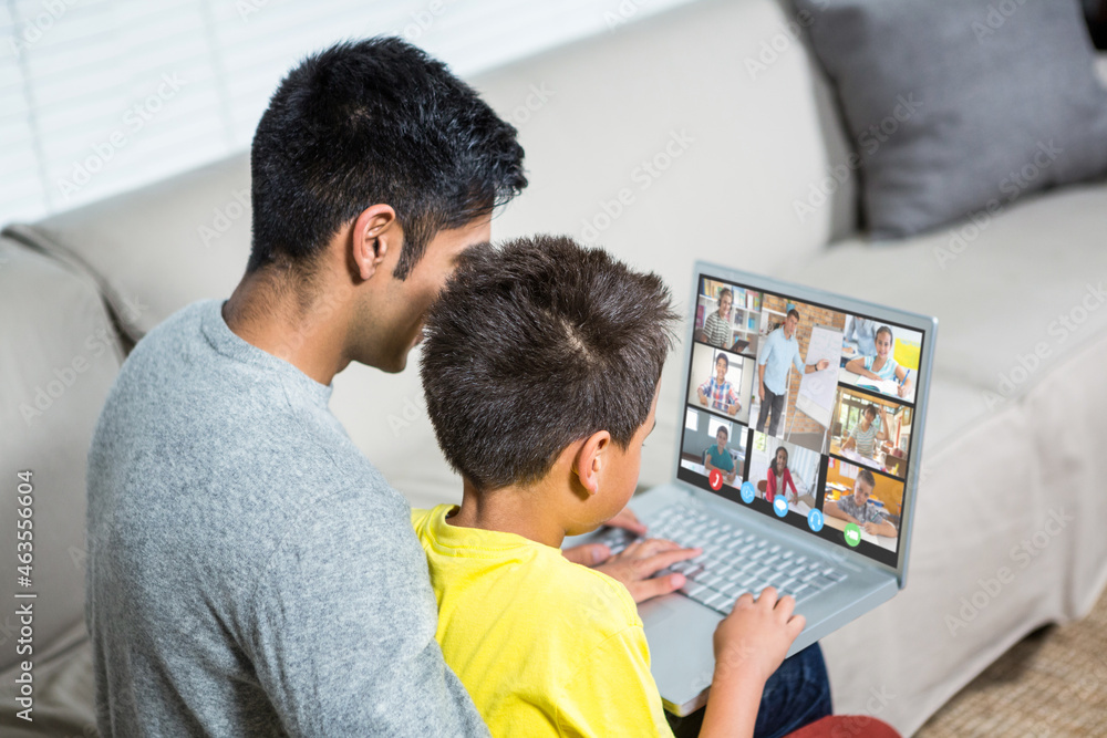 Wall mural Biracial boy with father using laptop for video call, with elementary school pupils on screen