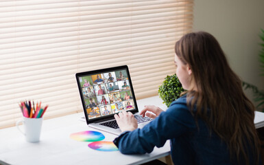 Obraz premium Caucasian girl using laptop for video call, with smiling diverse elementary school pupils on screen