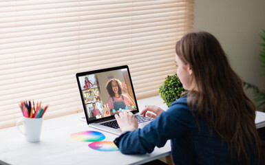 Fototapeta na wymiar Caucasian girl using laptop for video call, with smiling diverse high school pupils on screen