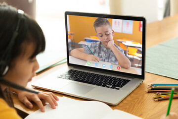 Fototapeta na wymiar Asian girl using laptop for video call, with elementary school pupil on screen
