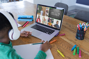 African american boy using laptop for video call, with diverse elementary school pupils on screen - Powered by Adobe