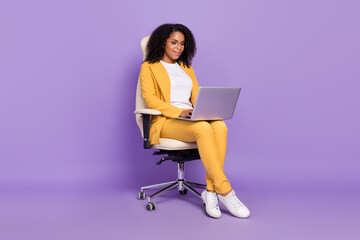 Fototapeta na wymiar Photo of shiny cute woman dressed yellow suit spectacles sitting chair typing modern device isolated violet color background