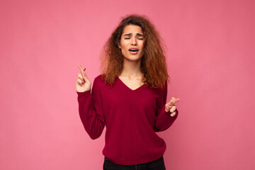Photo shot of young attractive brunette curly woman with sincere emotions wearing trendy pink...