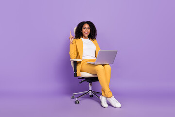 Photo of cute excited woman dressed yellow suit spectacles sitting chair chatting modern device isolated violet color background