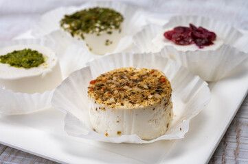 Cheese collection, variety of fresh white soft goat French cheeses with aromatic herbs, berries and green pesto
