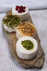 Cheese collection, variety of fresh white soft goat French cheeses with aromatic herbs, berries and green pesto