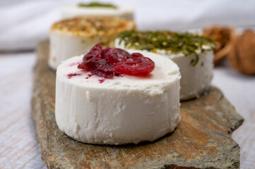Cheese collection, variety of fresh white soft goat French cheeses with aromatic herbs, berries and green pesto