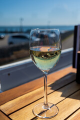 Glass of white wine served on outdoor terrase with seaview, summer vacation