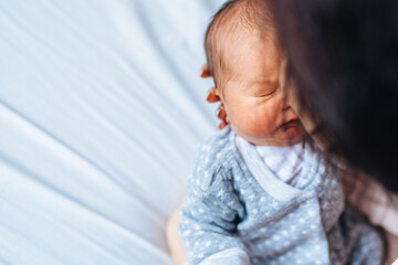 Young caucasian woman bonding nad kissing little newborn kid at home, copy space. Love and tenderness, motherhood concept.