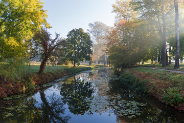 Fototapeta na wymiar Water canal in the autumn park at sunny morning