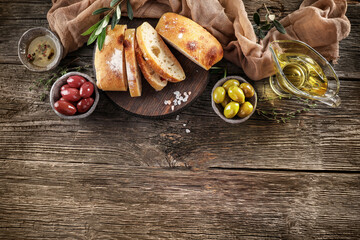 Virgin olive oil, olives and fresh bread on the table. Top view