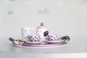 Pink toy mini tea set on gray background. Small toy tea cups and teapot. Coffee set on gray.