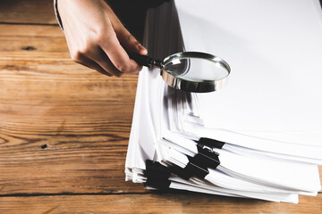 woman holding magnifying glass and documents