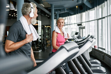 Fototapeta na wymiar Happy senior couple on treadmills in gym