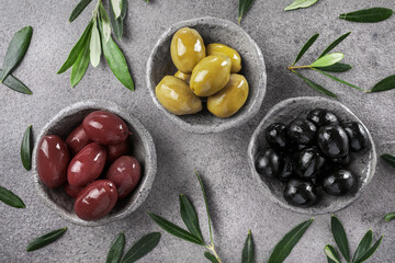 Green, black and red olives and olive oil on stone table. Top view