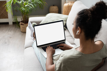 Young woman using laptop computer at home. Blank empty white screen mock up. Freelance, student lifestyle, education, web conference, video call, technology and online shopping concept