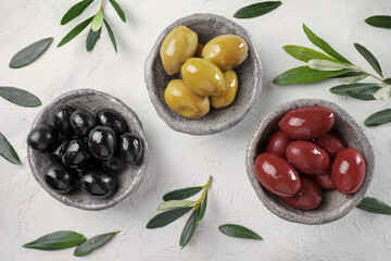 Green, black and red olives and olive oil on stone table. Top view