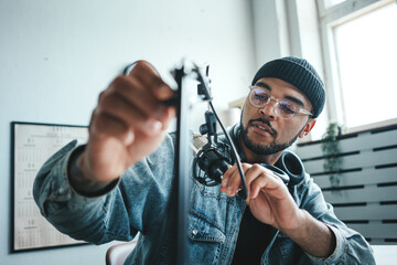 Cheerful mixed race host tuning his microphone at small and cozy home broadcast studio