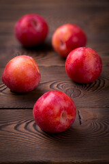 Fototapeta na wymiar Red plum scattered on a wooden table, dark rustic vertical photo