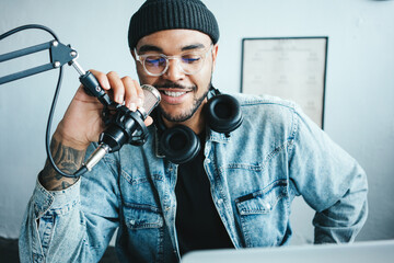 Cheerful and smiling mixed race host streaming his audio podcast at small and cozy home broadcast studio