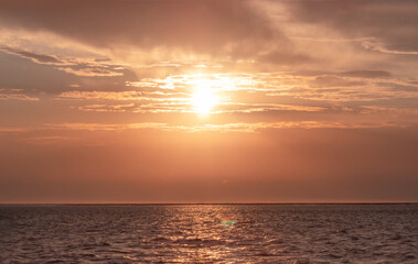 Naklejka premium Colorful red sunset and bright sun on the horizon of the ocean beach.