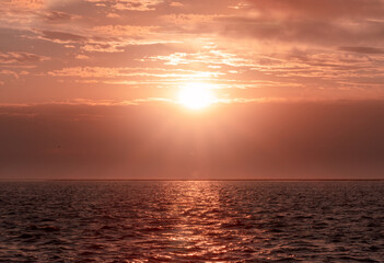 Obraz premium Colorful red sunset and bright sun on the horizon of the ocean beach.