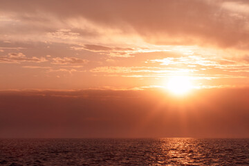 Colorful red sunset and bright sun on the horizon of the ocean beach.