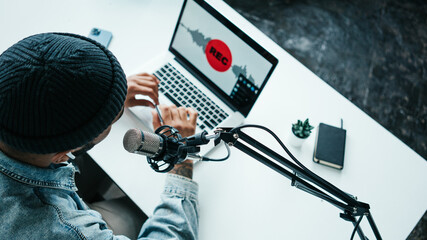 Mixed race content creator streaming his live podcast using professional microphone at his broadcast studio, top view