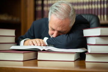 Sleepy businessman lawyer surrounded by many books