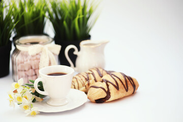 French breakfast on the table. Coffee croissant with chocolate and a decanter with cream. Fresh pastries and decaffeinated coffee.