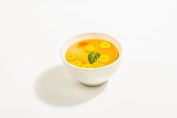 Transparent chicken broth with vegetables in ceramic bowls
