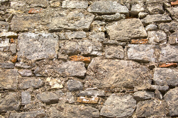 Stone antique old wall as a background or texture. Vintage background of a fortress wall in loft and grunge style with place for text and copy space.