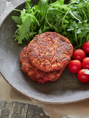 close-up view of homemade veggie burgers, rocket and cherry tomatoes on a dark rustic plate.  Alternative to meat.