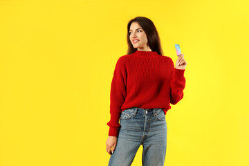 Attractive girl holds credit card on yellow background