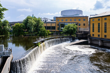 Industrial cityscape with old factory buildings and and water reservoir with waterfall in Norrkoping Sweden.