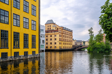 Cityscape view of old industrial buildings near city river with water reservoir in Norrkoping Sweden.