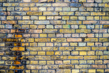 Outdoor closeup of old yellow worn and greasy vintage industrial brick wall.