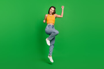 Fototapeta na wymiar Full size photo of young hooray brunette lady jump wear top jeans shoes isolated on green background