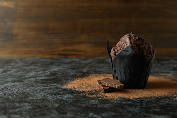 Tasty chocolate muffin on black smokey table