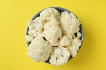 Fresh juicy cauliflower slices in bowl on yellow background