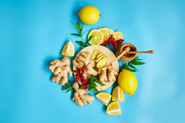 Flat lay of Immune boosting remedy, immunity boosting foods ginger, lemon,  honey,  guelder rose, mint on blue background Top view, copy space.