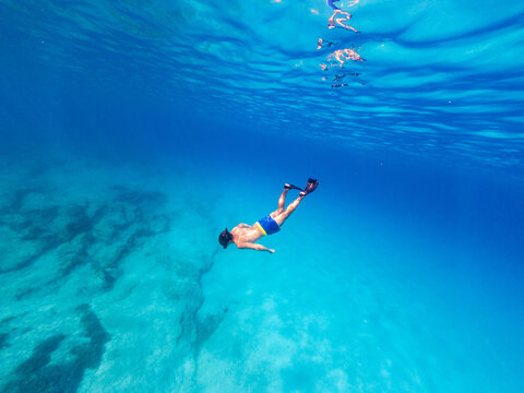 Underwater photo of man free diving in clear sea