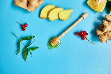 Flat lay of Immune boosting remedy, immunity boosting foods ginger, lemon,  honey,  guelder rose, mint on blue background Top view, copy space.