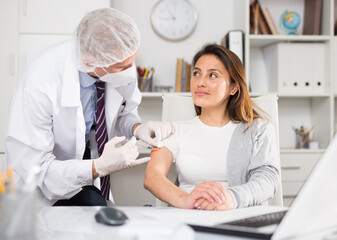 Doctor giving Covid-19 or flu antivirus vaccine shot to patient wear face mask protection at medical office