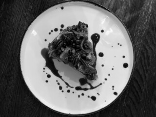 Apple charlotte sprinkled with walnuts, blueberries and figs on top. Black and white photo